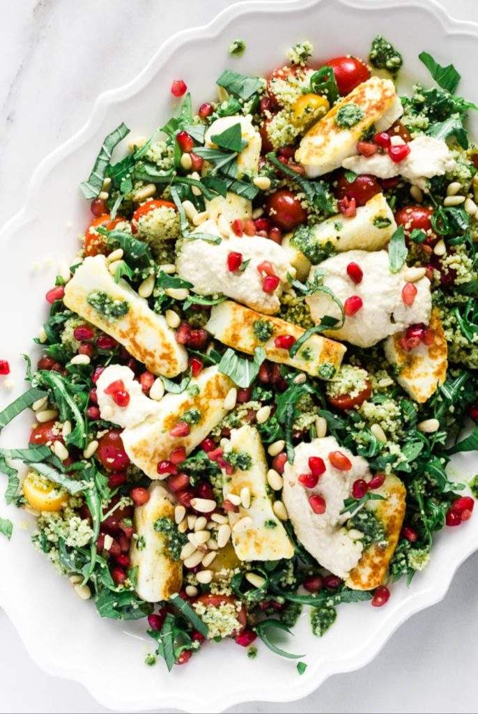 Halloumi Couscous Salad with pomegranate seeds, cucumber, red onion, and mint in a Mediterranean-style bowl.