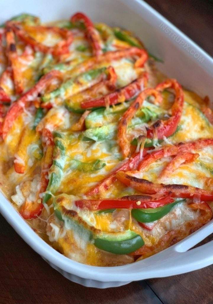 Cheesy Chicken Fajita Bake in a white casserole dish, topped with melted cheese, colorful bell peppers, and juicy baked chicken breasts – a one-pan Tex-Mex dinner.