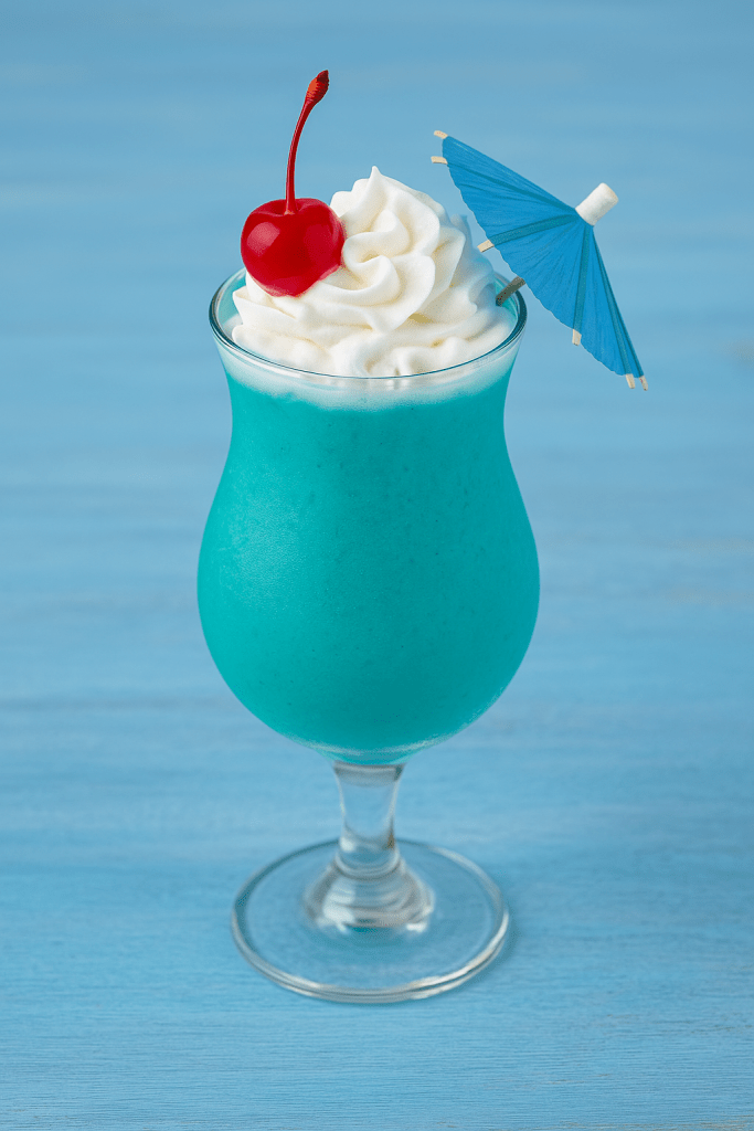 Make sure to upload an image of the drink with the alt text set to: Ocean Blue Piña Colada served in a tropical glass with whipped cream and cherry on top