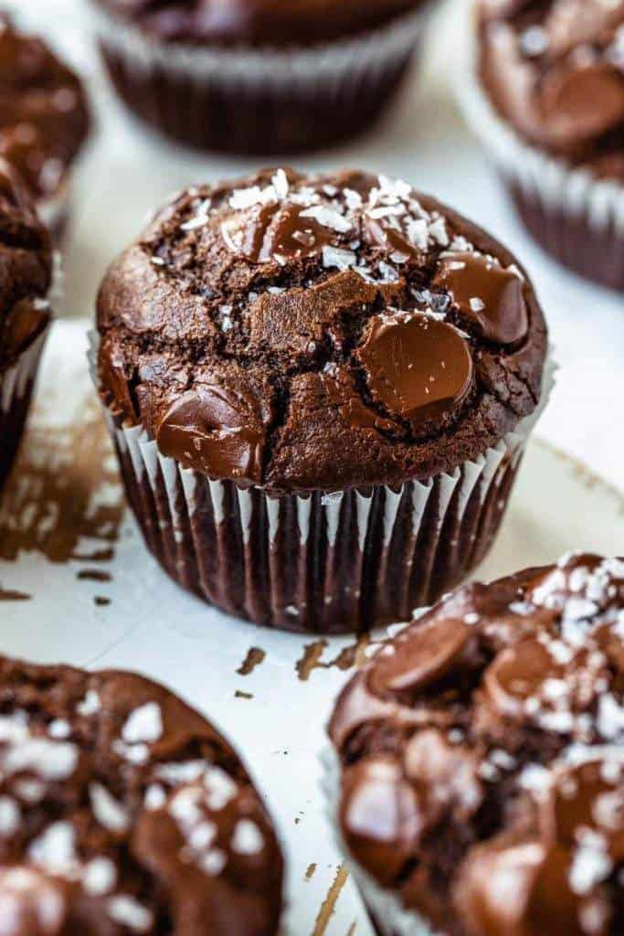 Freshly baked Double Chocolate Muffins topped with melted chocolate chips on a wooden background
